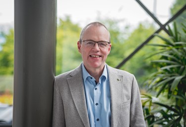 Man smiling to camera with plants in the background