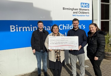 PM Group employees holding check outside Birmingham Children