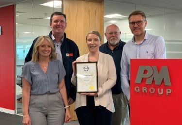 Group photo of the UK team holding their Gold RoSPA Award 2024 in the PM Group office building.