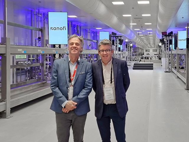 Two men pictured standing in a modular vaccine facility. 