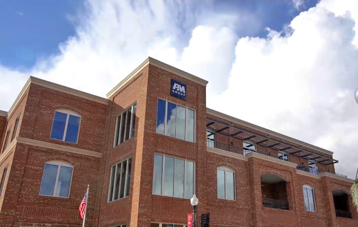 Image of a red brick building with the PM Group black and white logo placed at the top of the building.